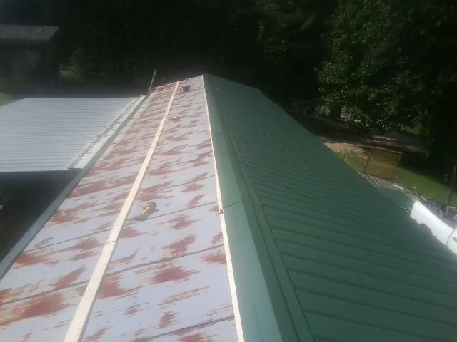 Old rusted panels beside newly installed green metal roofing — Wind Damage Roof Repair by Roofing Brothers in Stilesville