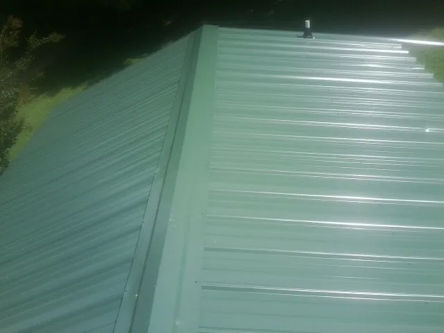 New green metal panels meeting at the ridge of a roof — Flat Roof Repair work by our crew in Stilesville