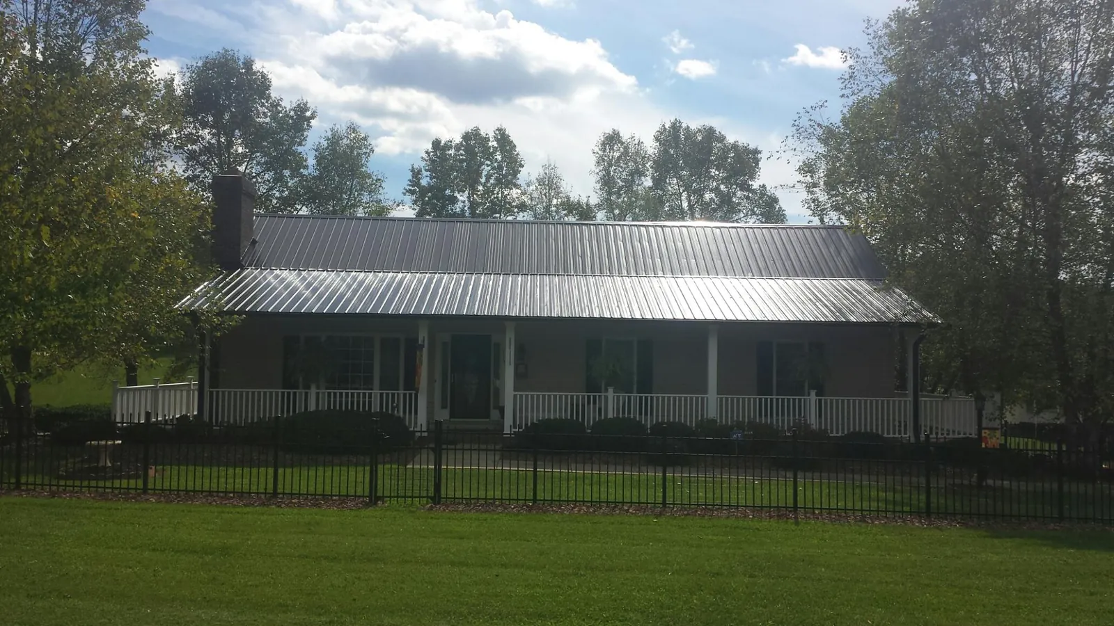 Gray metal roof on a brick ranch with a full width front porch — Gutter Guard Installation work by our crew in Stilesville
