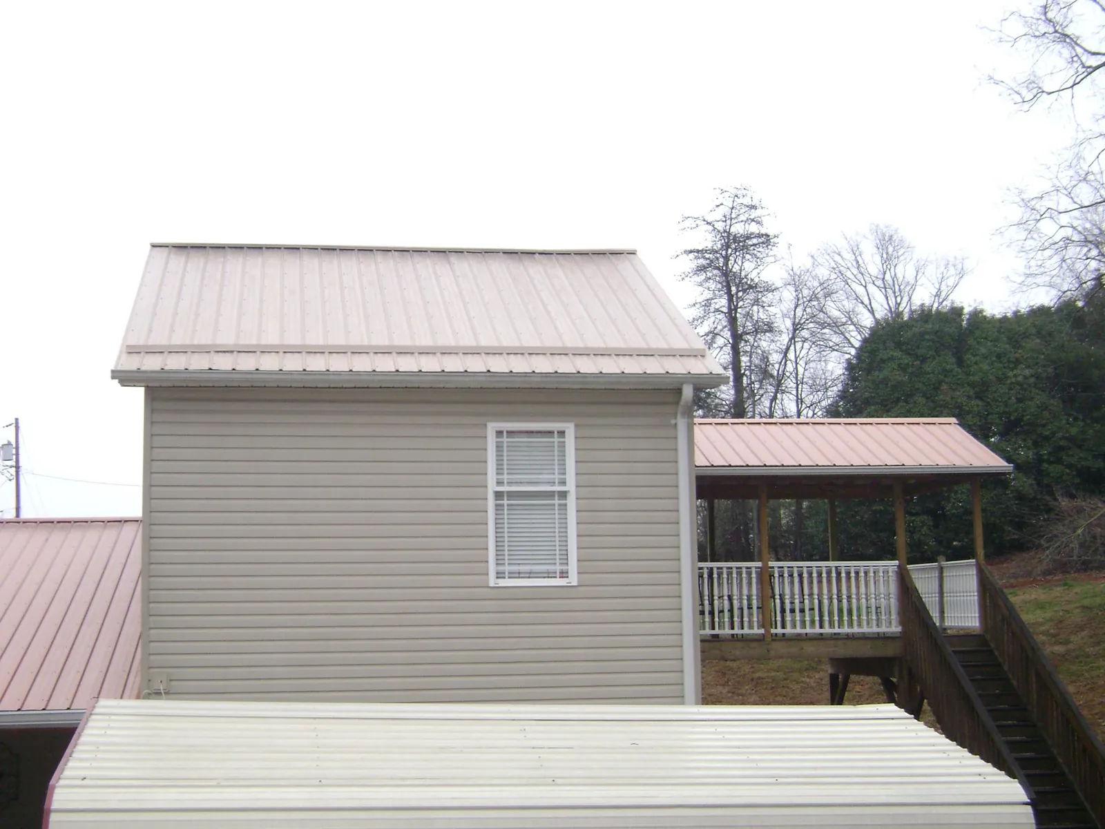 Tan metal roofs on a two story addition and attached porch, from a Roof Replacement job in Stilesville