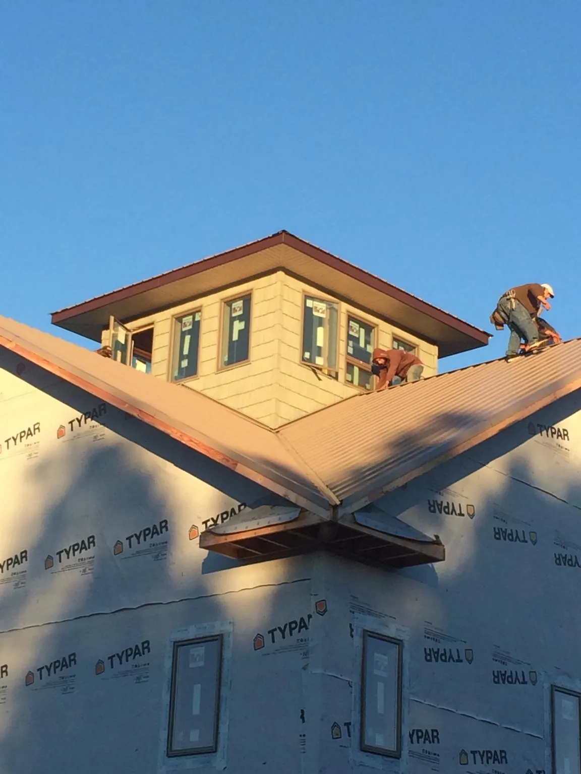 Roofers working around a rooftop cupola on a new metal roof at sunset — Roof Waterproofing in Stilesville by Roofing Brothers